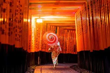 Walking through the lantern-lit torii gates of Fushimi Inari Shrine after dark