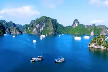 Cruise boats navigating the deep blue waters of Ha Long Bay, Vietnam, surrounded by lush limestone islands in this iconic UNESCO World Heritage seascape.