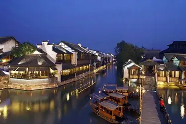 Traditional Chinese water town at night, illuminated canals and wooden boats reflecting lights in Wuzhen, China.