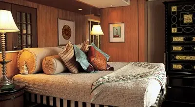 Luxurious suite at The Oberoi Amarvilas, Agra, featuring a daybed with plush cushions, warm wood-paneled interiors, elegant decor, and soft ambient lighting.