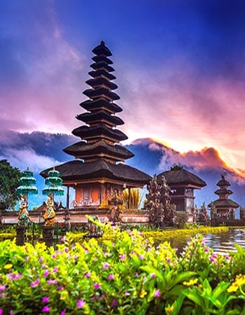 Ulun Danu Beratan Temple in Bali with its iconic multi-tiered pagoda set beside a reflective lake, framed by lush gardens and a dramatic sunset sky.