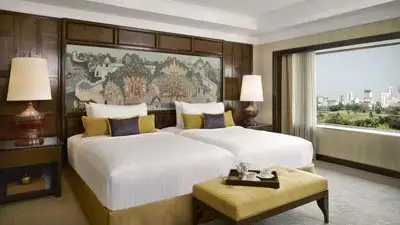 Elegant twin guest room at Anantara Siam Bangkok Hotel, featuring refined Thai décor, plush beds, classic furnishings, and large windows overlooking the city.