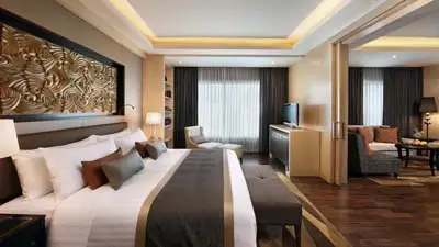 Deluxe guest room at Amari Bangkok hotel, featuring modern Thai-inspired design, a king bed, warm wood accents, and a spacious layout near Bangkok’s central shopping and transit districts.