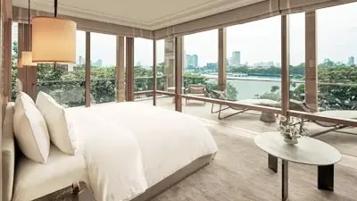 Riverfront guest room at Capella Bangkok, featuring floor-to-ceiling windows, refined contemporary design, and panoramic views of the Chao Phraya River in a serene luxury setting.