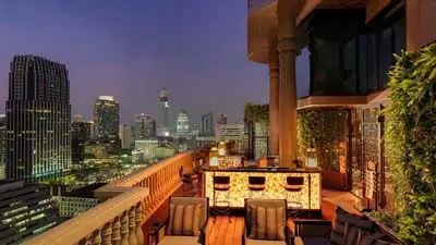 Rooftop bar at Hotel Muse Bangkok overlooking the city skyline at night, featuring stylish seating, warm ambient lighting, and panoramic views of Bangkok’s high-rise district.