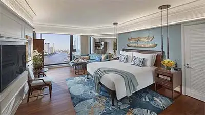 Luxury guest room at Mandarin Oriental Bangkok, featuring elegant contemporary décor, a plush king bed, and expansive windows overlooking the Chao Phraya River.