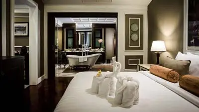 Guest room at Na Nirand Romantic Boutique Resort Chiang Mai, featuring elegant décor, a plush bed with towel art, and an en-suite bathroom, conveniently located near the city center and riverside attractions.