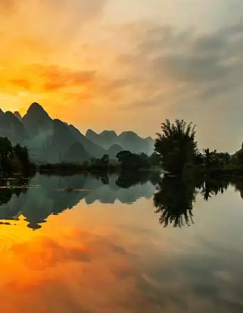 Sunrise over the Li River in Guilin with karst mountains reflected on calm water, highlighting southern China’s iconic natural scenery.