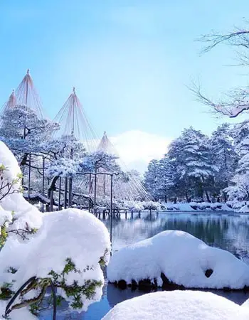 Winter landscape at Kenrokuen Garden, Kanazawa, featuring snow-laden pines and reflective water