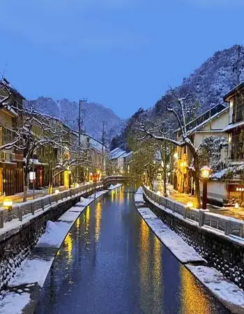Snow and mountain silence frame Kinosaki's historic canal district, where reflected lantern light honors centuries of thermal tradition