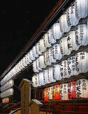 Osaka's lantern-lit festival night illuminates tradition—paper and shadow dancing against darkness, where celebration honors centuries of ritual