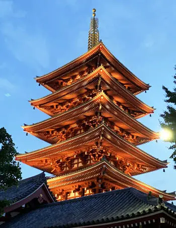 Golden-lit five-tiered pagoda at Sensoji Temple in Tokyo, a historic Buddhist architectural landmark