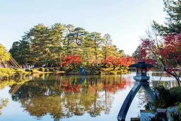 Kenrokuen Garden in Kanazawa with stone lantern and autumn foliage reflected in the pond
