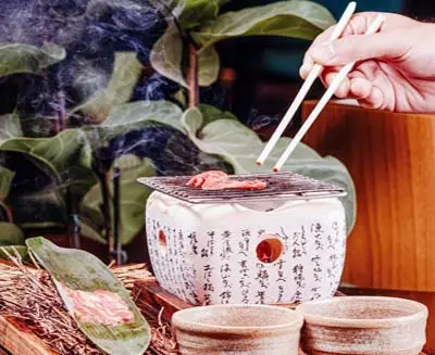 At Cooking Sun, a student's hands guide chopsticks into steaming broth, transforming Japanese culinary technique from observation to lived skill