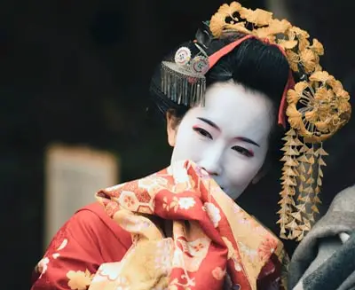 Woman in traditional Japanese attire with white makeup and ornate hair ornaments