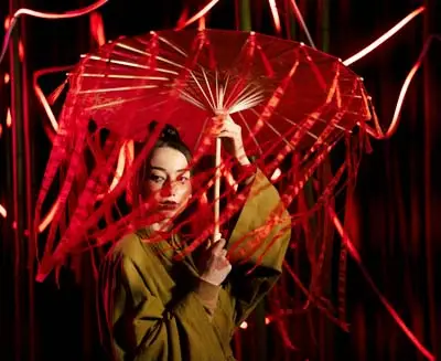 Performer in traditional costume holding a red umbrella during a Kabuki theater performance
