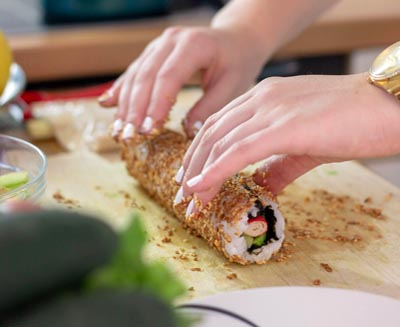 Hands rolling fresh sushi on a wooden board during a Japanese cooking experience