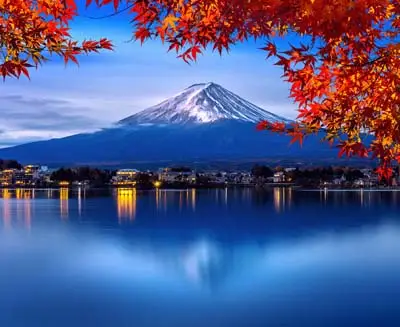 Iconic snow-crowned mountain emerging through crimson foliage in the liminal space between night and dawn