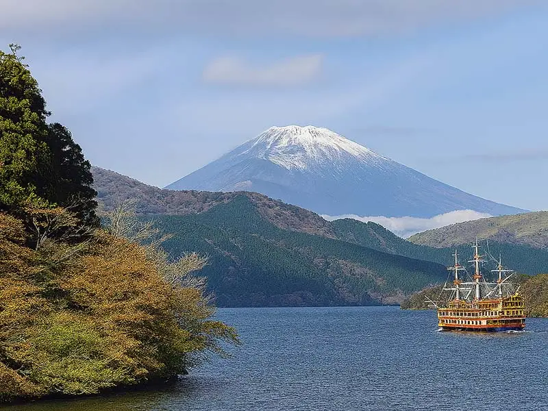 Mount Fuji rising above Lake Ashi in Hakone with a sightseeing pirate ship cruising across the water.