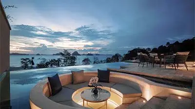Infinity-edge terrace at Banyan Tree Krabi overlooking the Andaman Sea at dusk, featuring curved lounge seating and panoramic coastal views in a tranquil luxury setting.