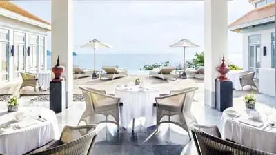 Oceanfront dining terrace at Amatara Welleisure Resort Phuket, featuring elegant seating, white table settings, and panoramic views of the Andaman Sea in a serene wellness-focused setting.