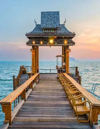 Wooden pier pavilion extending into the Andaman Sea on Koh Yao Yai, Thailand, featuring traditional Thai design and ocean views at sunset.