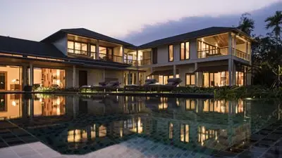 Legend Mekong Resort riverside villas with illuminated infinity pool at sunset, a tranquil luxury retreat in Vietnam’s Mekong Delta offering peaceful waterfront stays and easy access to regional waterways.