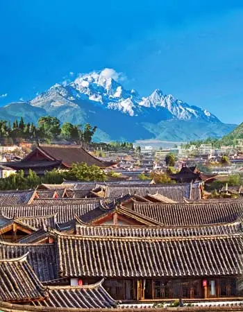 Lijiang Old Town rooftops with Jade Dragon Snow Mountain rising in the background, showcasing Yunnan’s cultural and scenic beauty.