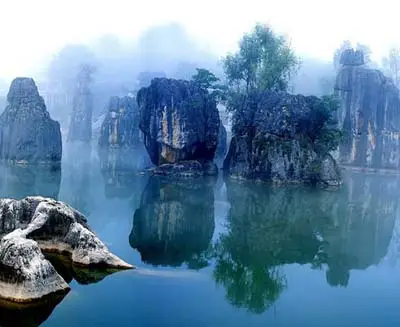Stone Forest in Kunming with dramatic limestone pillars reflected in calm water, showcasing Yunnan’s unique karst landscape.