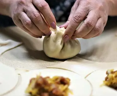Hands shaping a traditional Chinese dumpling during a hands-on cooking experience