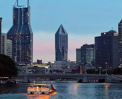 Huangpu River night cruise in Shanghai with illuminated skyline and skyscrapers reflected on the water.