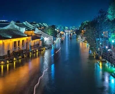 Wuzhen Water Town illuminated at night, with traditional houses lining a canal in China