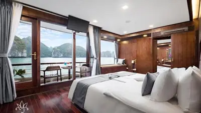 Luxury cabin aboard Orchid Classic Cruise on Ha Long Bay, Vietnam, featuring a private balcony with panoramic views of limestone karsts and emerald waters, designed for a refined overnight cruise experience.
