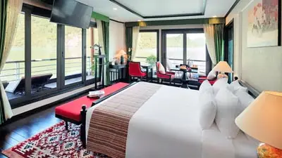 Spacious Orchid Premium cruise cabin on Ha Long Bay, Vietnam, featuring elegant décor, private balcony access, large windows, and comfortable seating with panoramic limestone karst views.