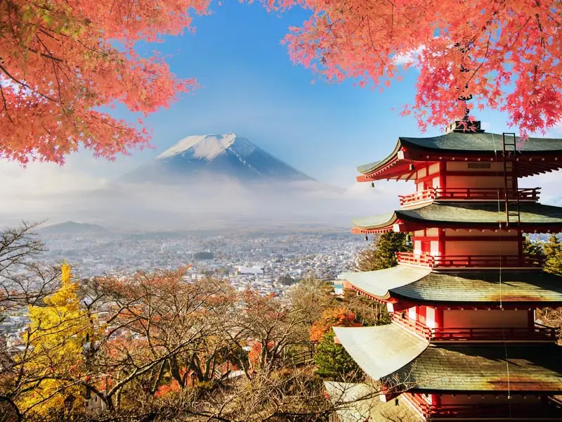 Chureito Pagoda overlooking Mount Fuji in autumn with red maple leaves framing the view above Fujiyoshida.