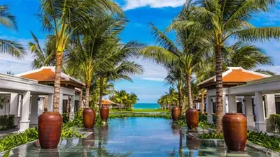 Beachfront resort pathway lined with palm trees in Cam Ranh, Vietnam, leading toward the turquoise sea and capturing the area’s relaxed coastal luxury.