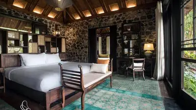 Elegant guest room at Tam Coc Garden Resort in Ninh Binh, Vietnam, featuring traditional stone walls, wooden furnishings, and a serene garden setting near Tam Coc’s limestone landscapes.