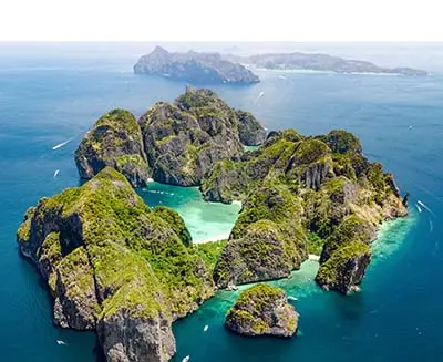 Aerial view of limestone karst islands and turquoise lagoons in southern Thailand, surrounded by deep blue Andaman Sea waters and dramatic tropical seascape.