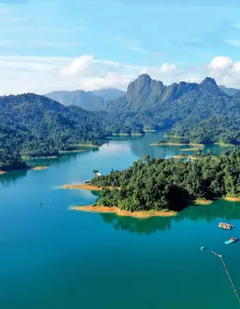 Aerial view of Cheow Lan Lake in Khao Sok National Park, Thailand, featuring emerald-green waters, forested islands, and dramatic limestone mountains.