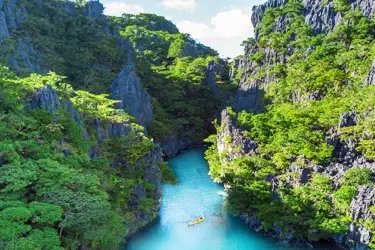 Narrow turquoise river winding through limestone karst cliffs in southern Thailand, surrounded by dense tropical forest and dramatic canyon scenery.