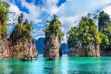 Longtail boats cruising turquoise waters among limestone karst islands at Khao Sok National Park.