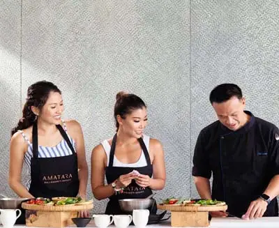 Guests participating in a Thai cooking class at Amatara Welleisure Resort Phuket, preparing traditional dishes with a professional chef in a hands-on culinary experience.