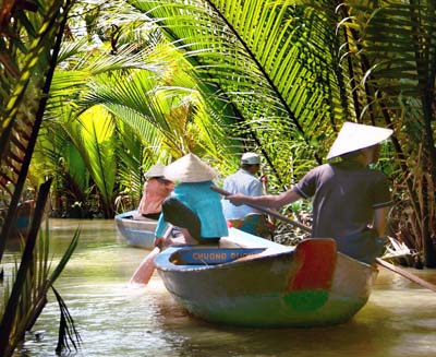 Travelers riding traditional basket boats through shaded coconut canals in Vietnam’s Mekong Delta, highlighting the region’s lush waterways and local river life.