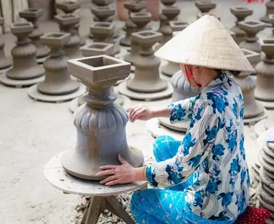 Local pottery artisan crafting traditional ceramics at a pottery village near Hanoi, showcasing handmade Vietnamese pottery techniques and cultural craftsmanship.