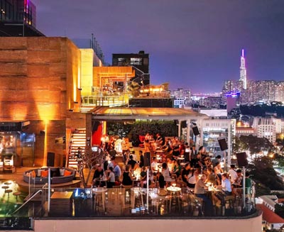 Rooftop bar overlooking the illuminated skyline of Saigon (Ho Chi Minh City), Vietnam, offering vibrant nightlife, panoramic city views, and an upscale urban atmosphere.