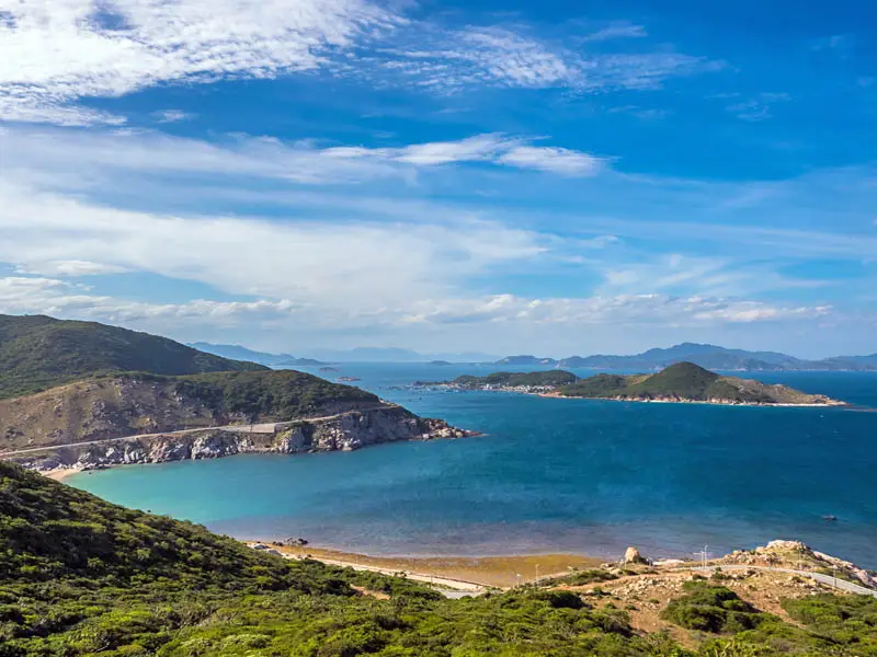 Coastal landscape of Ninh Van Bay near Nha Trang with turquoise water, rocky peninsulas, and lush green hills under a clear blue sky