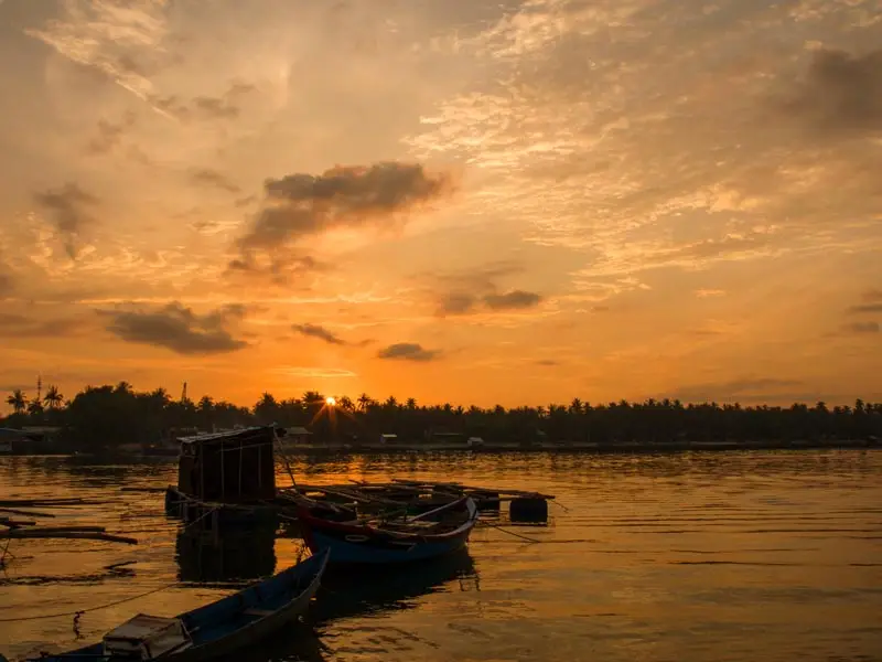 Scenic Phu Quoc shoreline at sunset with wooden fishing boats—luxury traveler’s dream seascape”