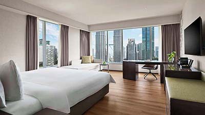 Modern city-view guest room at Traders Hotel Kuala Lumpur overlooking the Petronas Twin Towers and KL skyline, Malaysia