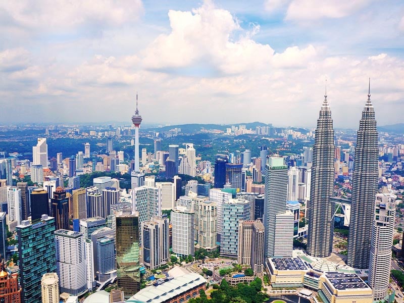 Cityscape of Kuala Lumpur with iconic towers rising over a blend of urban architecture and green spaces
