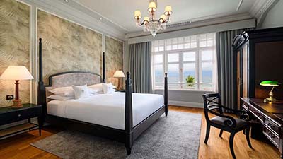 Elegant luxury accommodation at Penang’s East & Oriental Hotel with classic timber furnishings and expansive ocean-facing windows